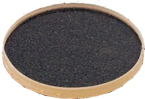 Schwarze runde Platte mit hellem Rand, möglicherweise für einen Brenner oder Kochfeld, besteht aus festem Material. Marke Wolf ist erkennbar.